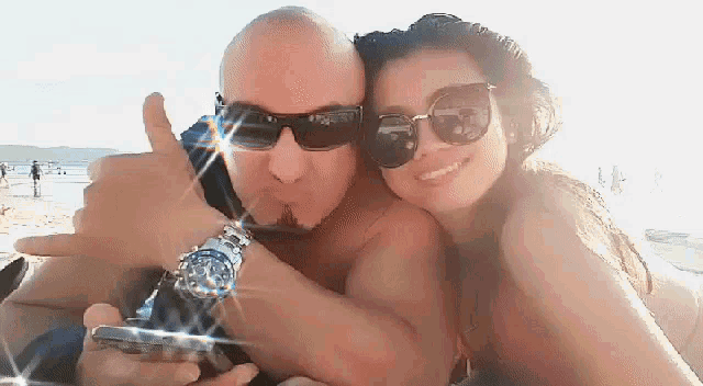 a man wearing sunglasses and a watch is hugging a woman
