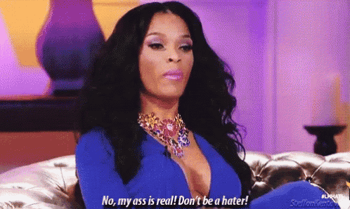 a woman is sitting on a couch and saying no , my ass is real !