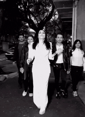 a woman in a white dress is surrounded by people