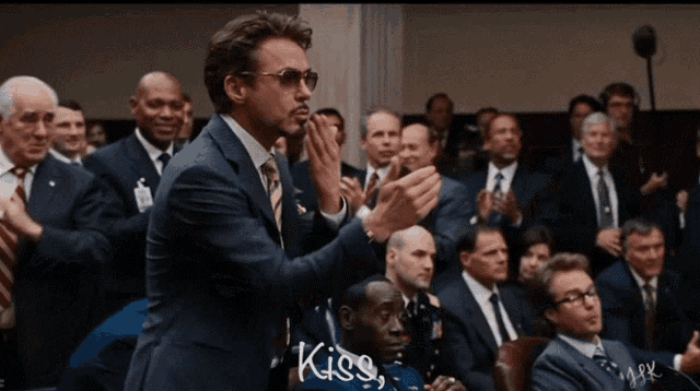 a man in a suit blows a kiss to a crowd