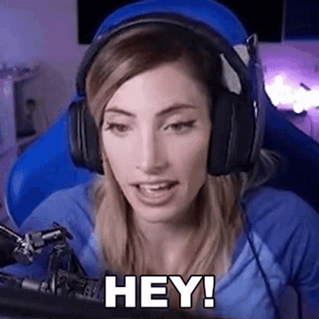 a woman wearing headphones and a blue shirt is sitting in front of a microphone .