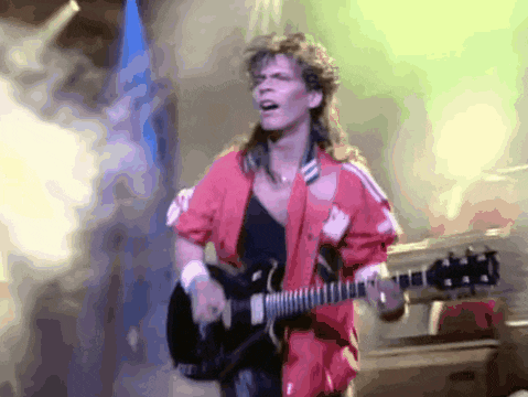 a man in a red jacket is playing a guitar on a stage