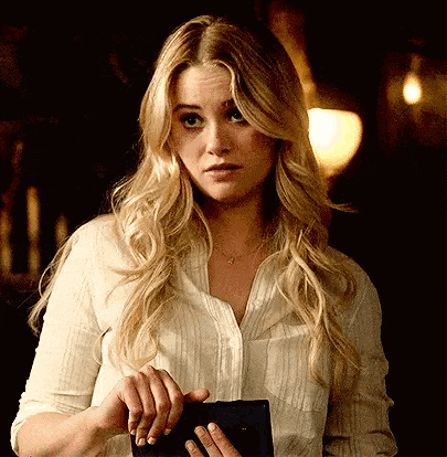 a woman in a white shirt is holding a wallet and looking at the camera .