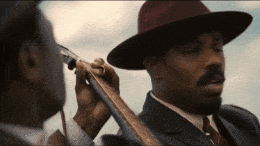 a man in a hat is playing a guitar next to another man in a suit