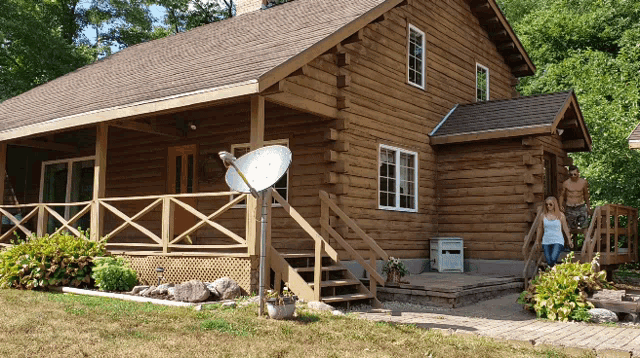 a couple standing outside of a log cabin