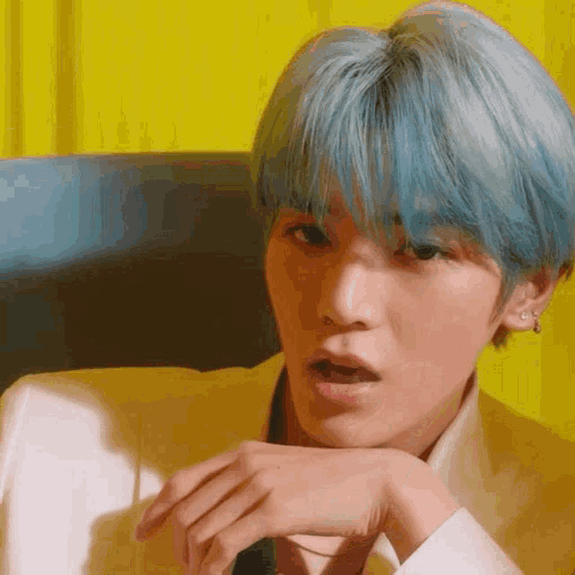 a close up of a person with blue hair wearing a white suit and tie .