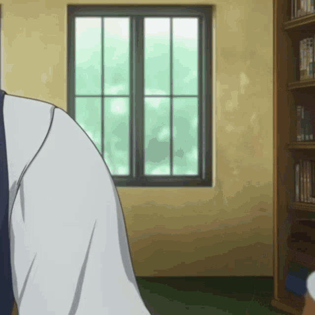 a man stands in front of a window in a room with bookshelves