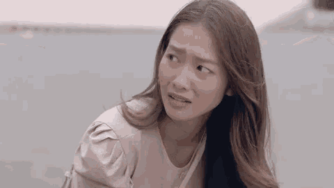 a woman with long hair is making a funny face while sitting on the ground .