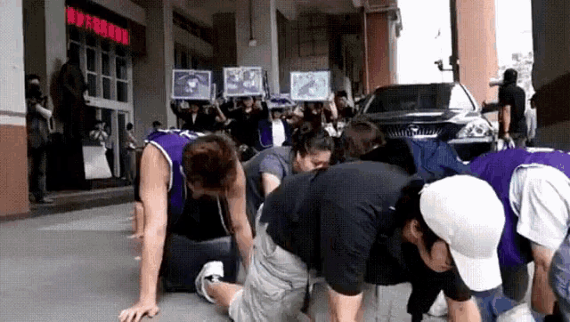 a group of people are kneeling down on the ground while holding signs