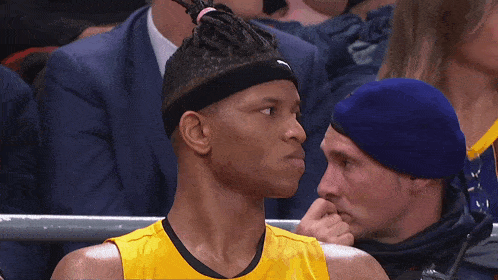 a man wearing a headband is sitting in the stands looking at something