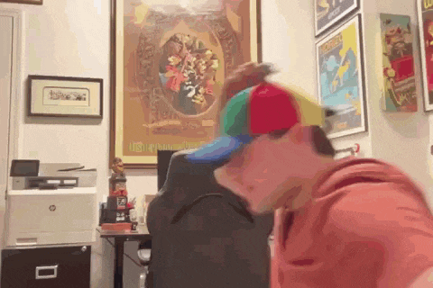 a man wearing a colorful hat is sitting at a desk in front of a hp printer