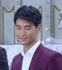 a man wearing a purple suit and white shirt is smiling with his eyes closed .