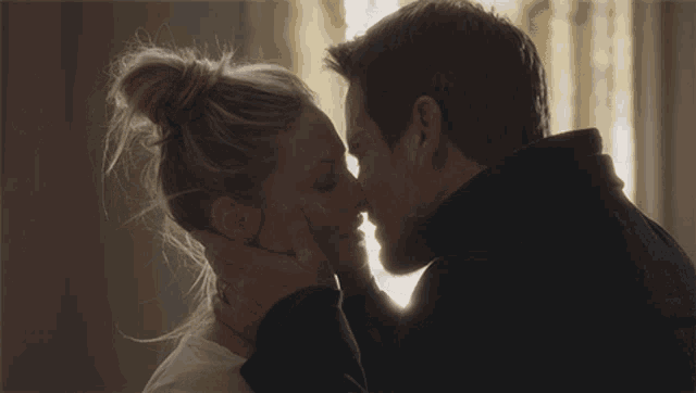 a man and a woman are kissing and the woman is holding the man 's face