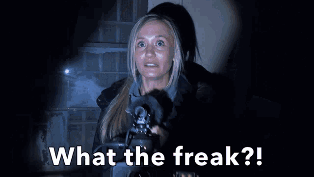 a woman in a dark room with the words what the freak written below her