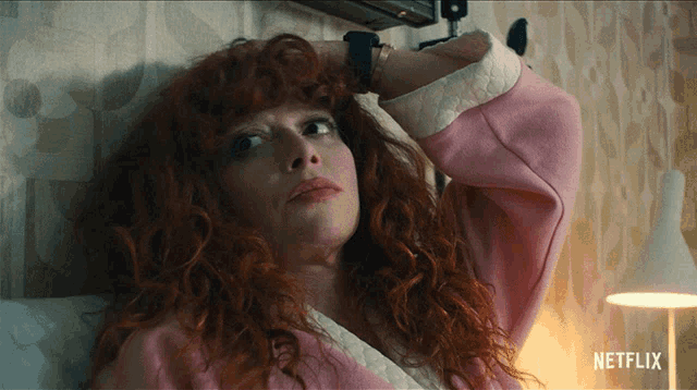 a woman with red hair is laying on a bed next to a lamp and a sign that says netflix