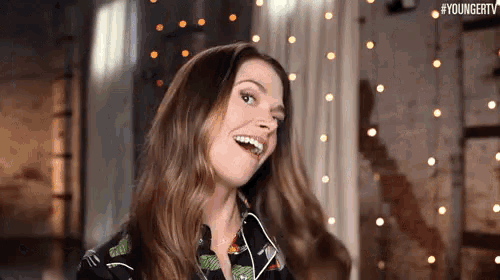 a woman is wearing headphones and smiling while standing in a room .