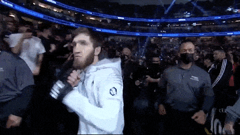 a man in a white hoodie is walking through a crowd in a stadium .