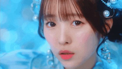 a close up of a girl 's face wearing a blue dress