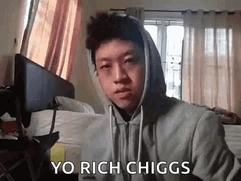 a man in a hoodie says yo rich chiggs in front of a bed .