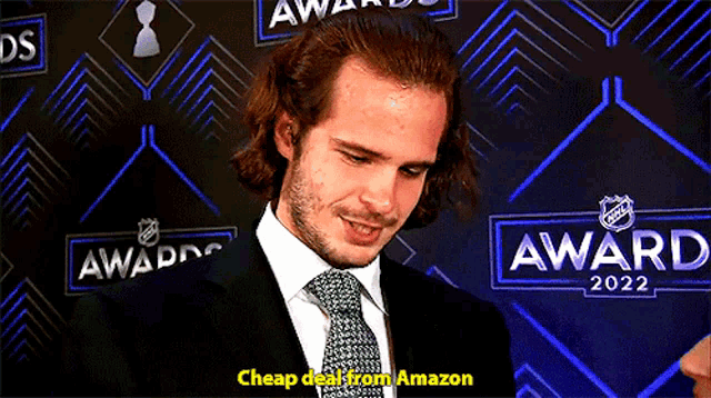 a man in a suit and tie is standing in front of a wall that says awards 2022