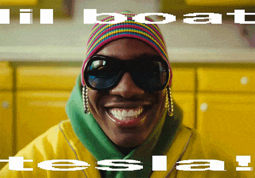 a man wearing sunglasses and a beanie is smiling with the words ' lil boat tesla ' above him