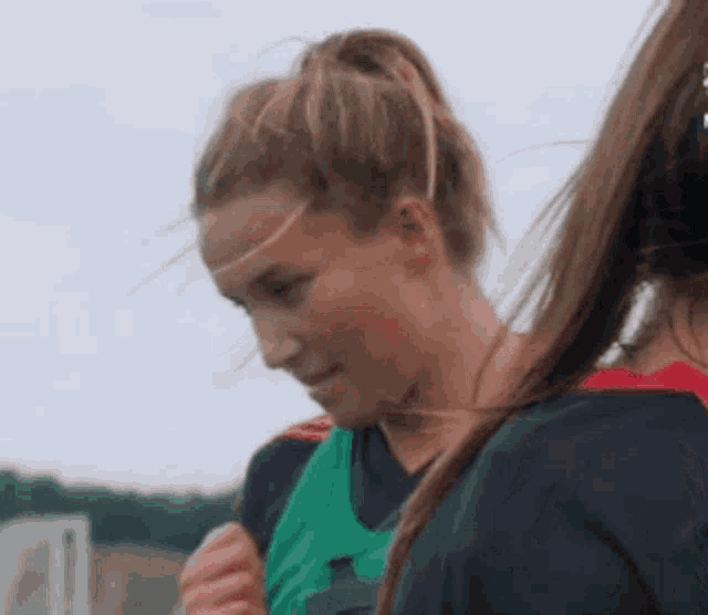 a woman in a green vest is standing next to another woman