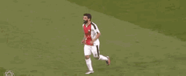a soccer player in a red and white jersey is running on a field .