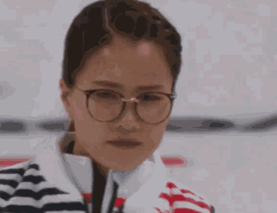 a woman wearing glasses and a striped jacket looks down
