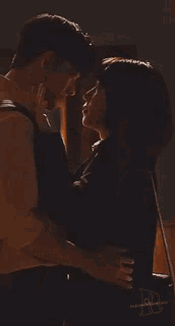 a man and woman are hugging and kissing in a dark room