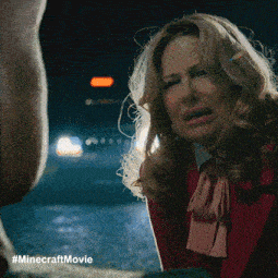 a woman in a red coat is talking to a man in a minecraft movie poster