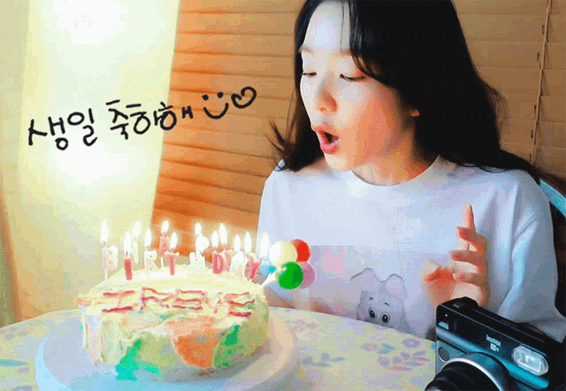 a woman blows out candles on a birthday cake with korean writing behind her