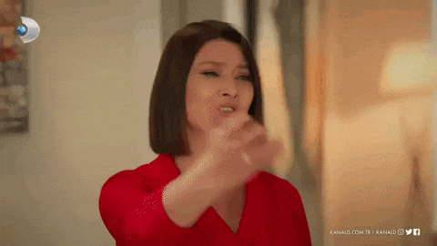 a woman in a red dress is making a funny face and pointing at the camera .
