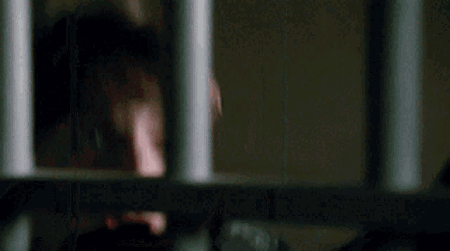 a close up of a person behind bars with a surprised look on their face