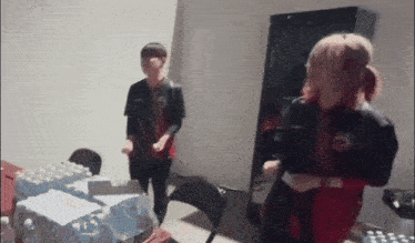 a man and a woman are dancing in a room with bottles of water on the table