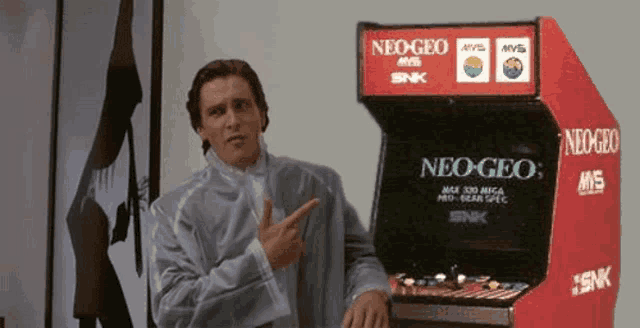 a man is pointing at a neo-geo machine