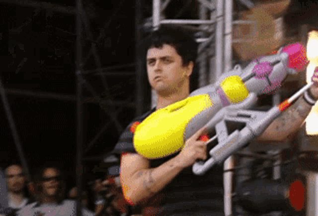 a man is holding a large yellow water gun in his hand