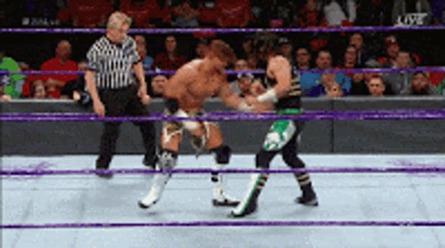 two wrestlers are fighting in a ring with a referee in the background