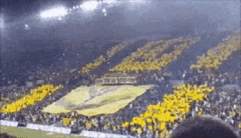 a crowd of people watching a soccer game with a large yellow banner that says ' a ' on it
