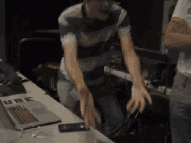 a man is standing in front of a table with a laptop and a sign that says tube
