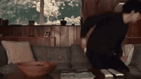 a man is standing in a living room next to a couch and a table .