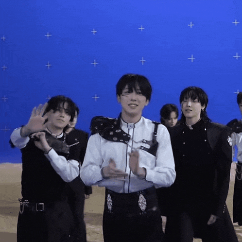 a group of young men are standing in front of a blue background
