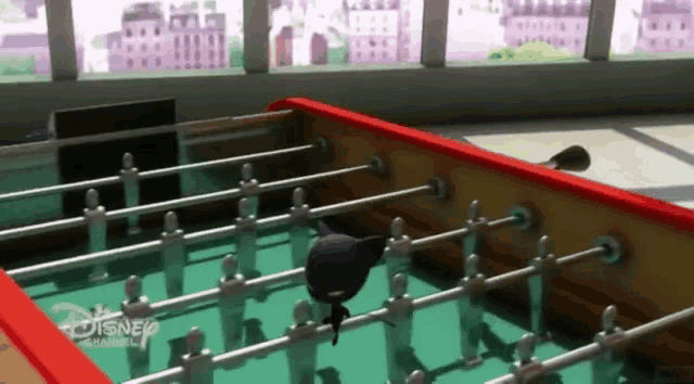 a cartoon character is playing a game of foosball on a table with a disney logo on it .