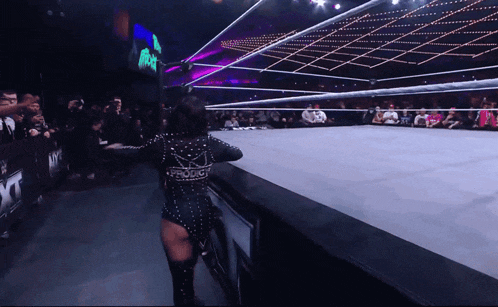 a woman in a wrestling ring is wearing a black bodysuit that says wwe on the back