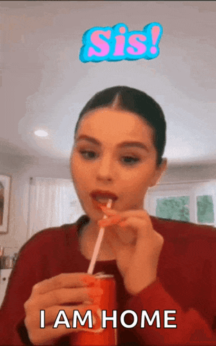 a woman is drinking a can of soda through a straw and says i am home .