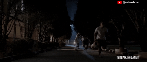 a man is walking down a dark street with the words terbaik ke langit written on the bottom