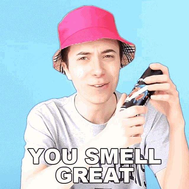 a man wearing a pink hat and a gray shirt with the words you smell great