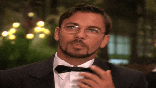a man with glasses and a beard wearing a tuxedo and bow tie