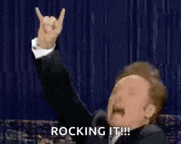 a man in a suit is making a horns sign with his hand .