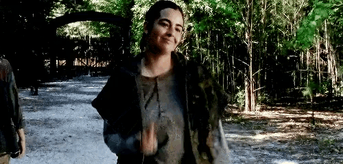 a woman is walking down a path in the woods and smiling