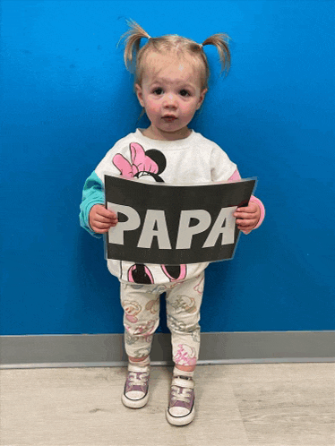 a little girl in a minnie mouse shirt holds up a sign that says papa
